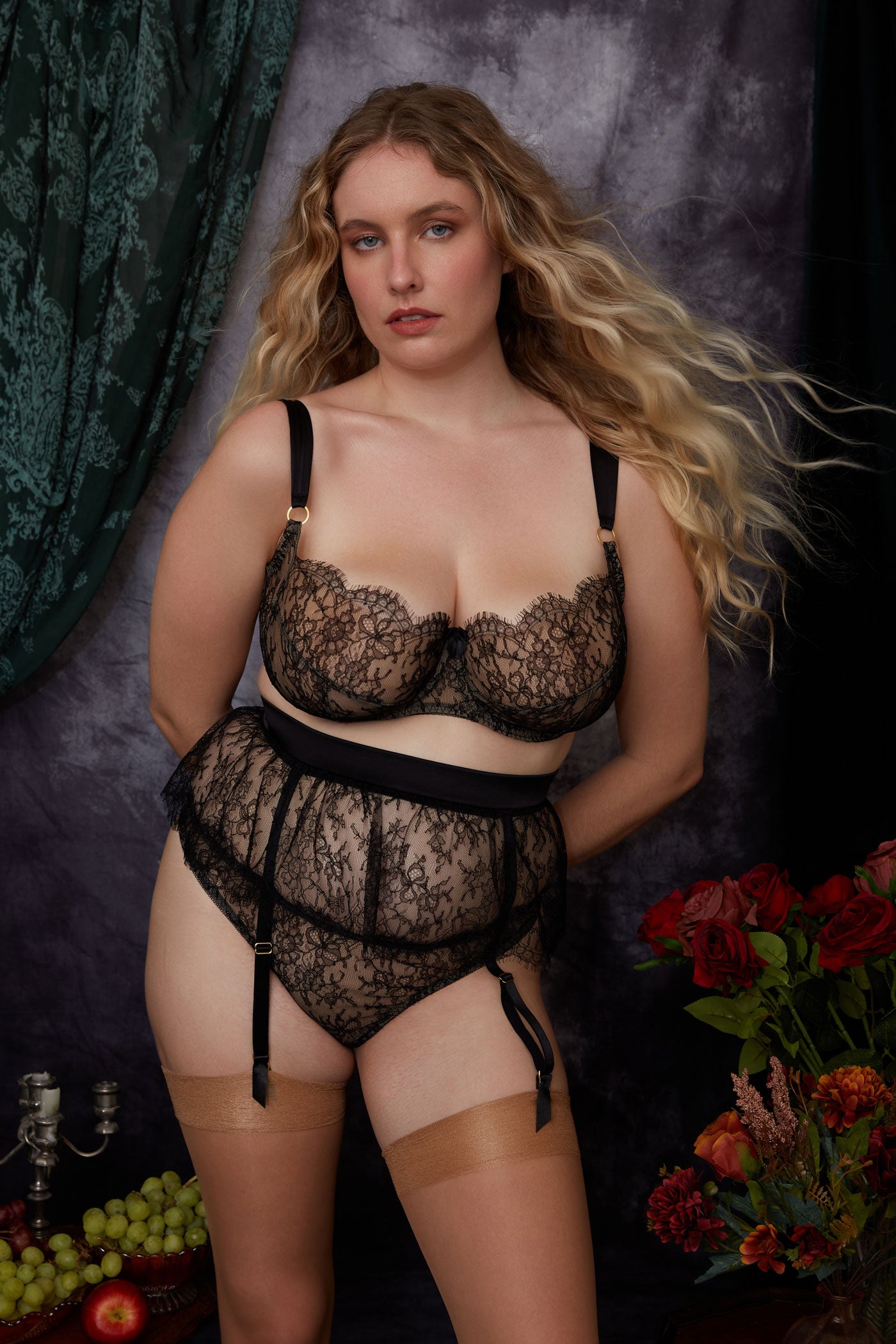 Luxury black lace lingerie set with skirted garter belt, styled with fruit and flowers