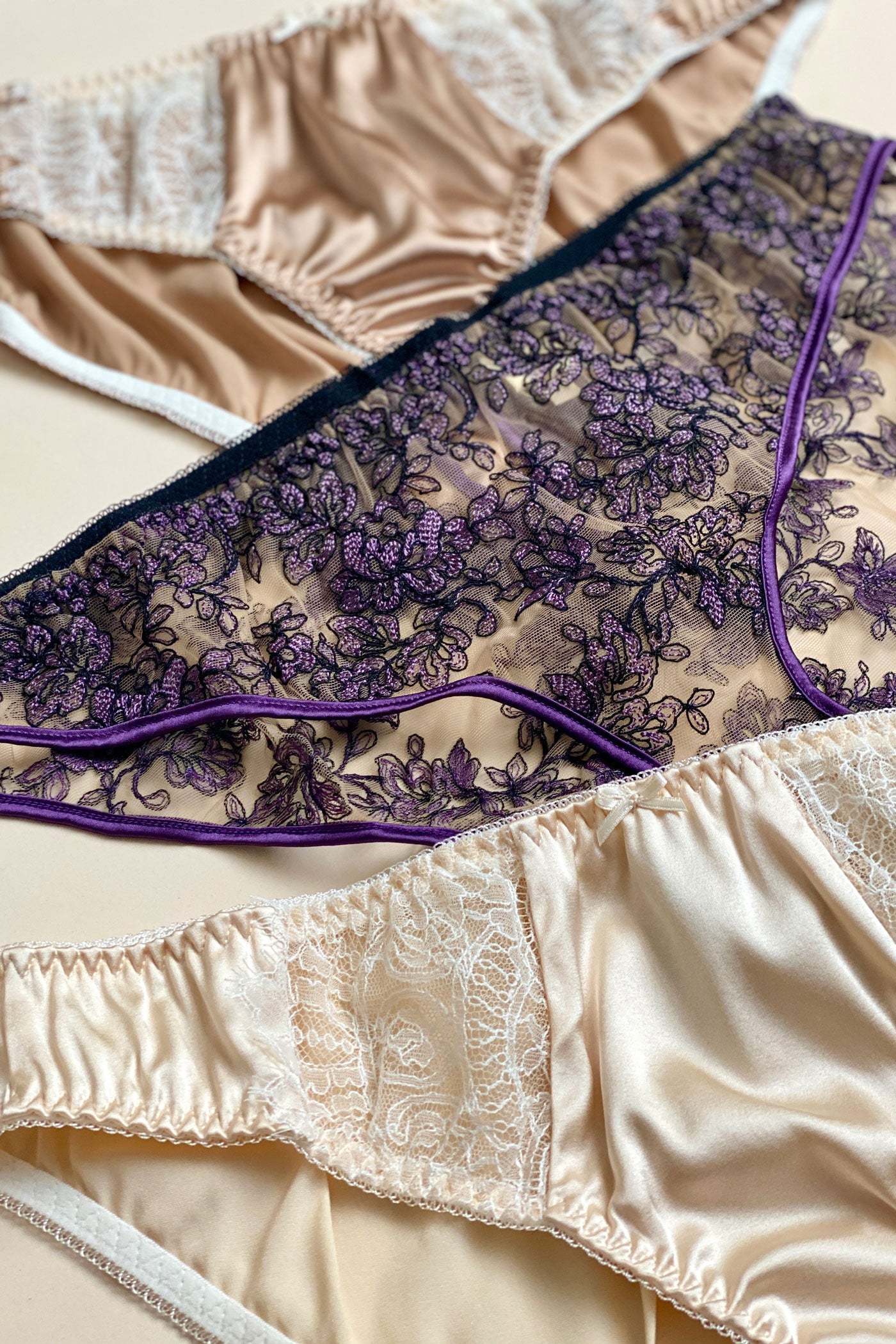 Close up detail of texture with sheer purple floral embroidery and cream silk