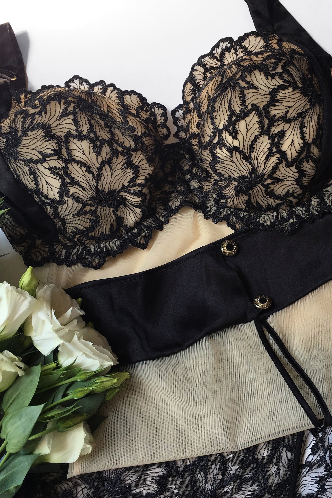 Flatlay detail of luxury black lace bra with sheer embroidery and matching tulle skirt