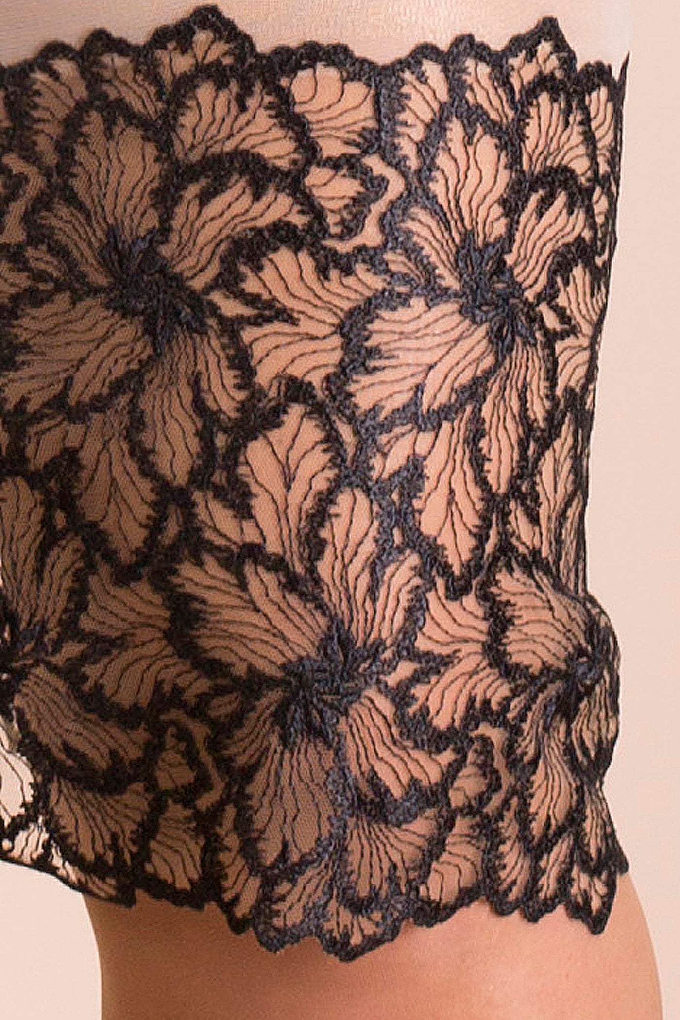 Detail of deep embroidery trim with black abstract floral design on sheer gold mesh with scalloped edges