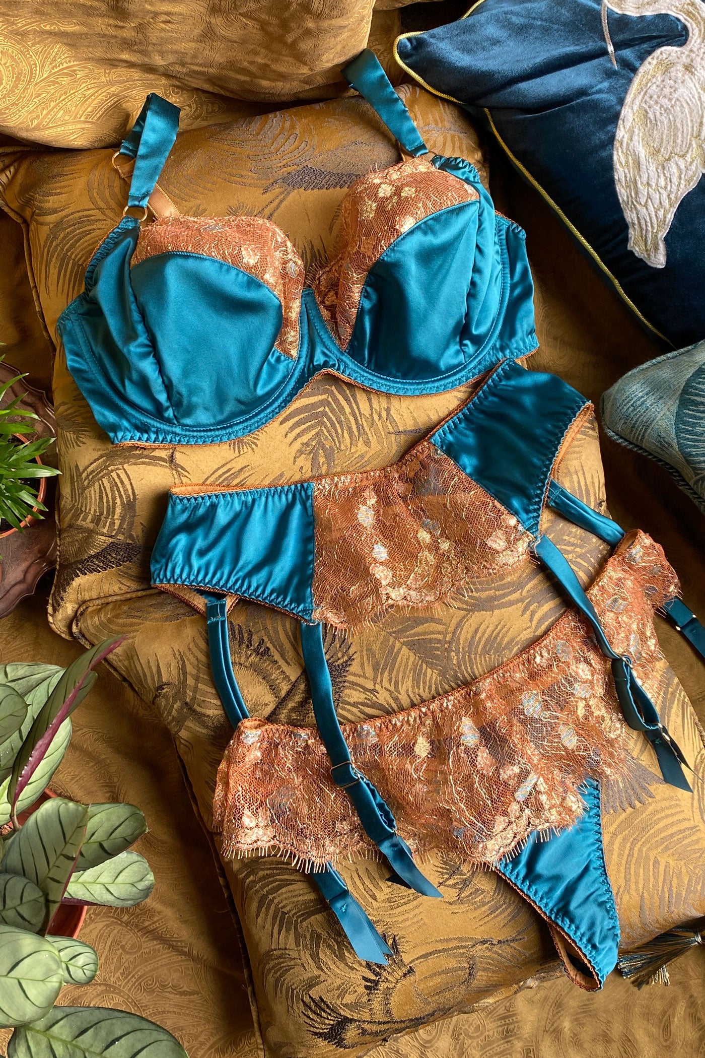 Silk and lace lingerie set in turquoise and gold with garter belt, DD+ bra and thong laid on gold cushions