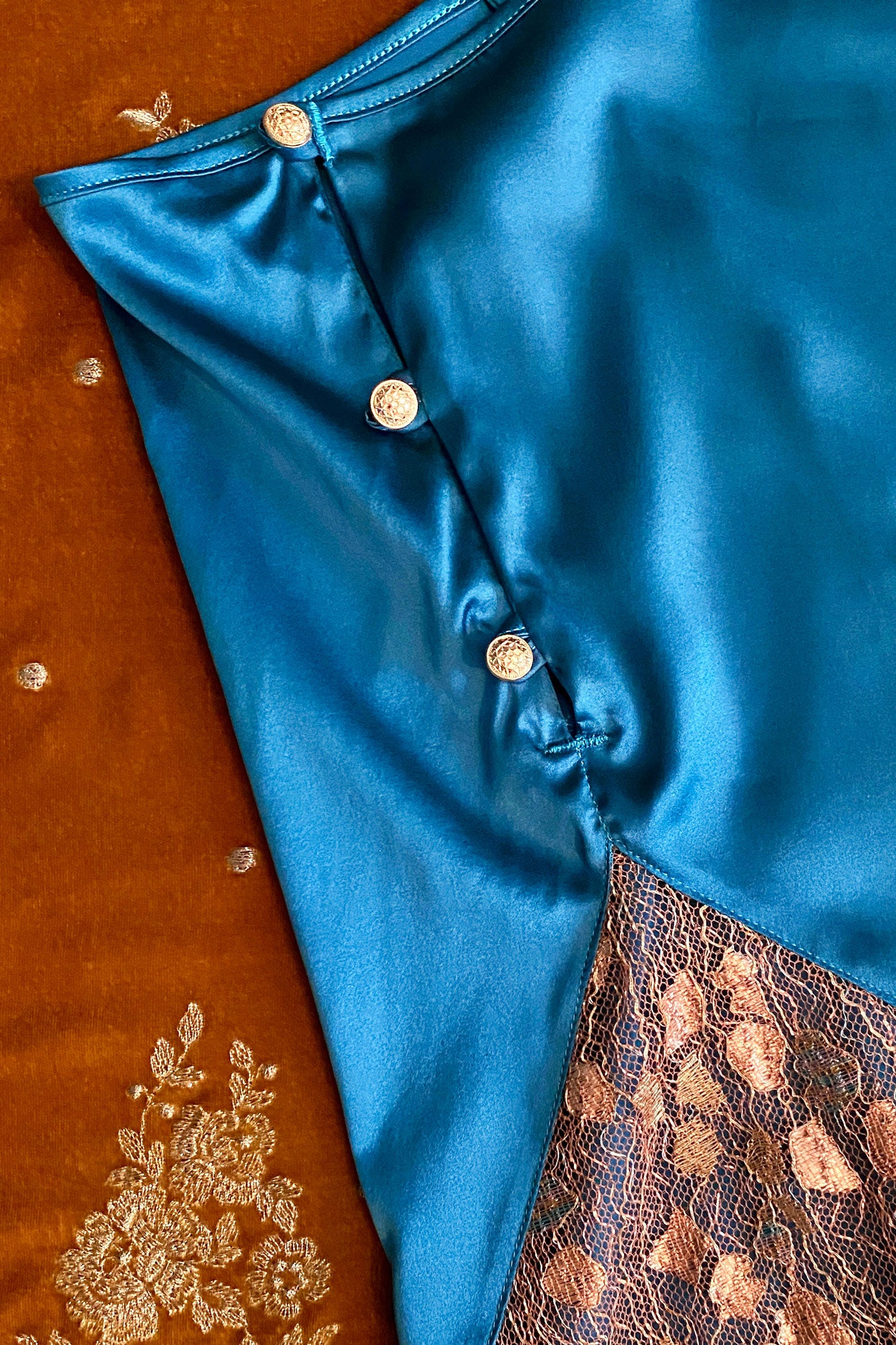 Button detail on blue silk tap pants with gold lace insert