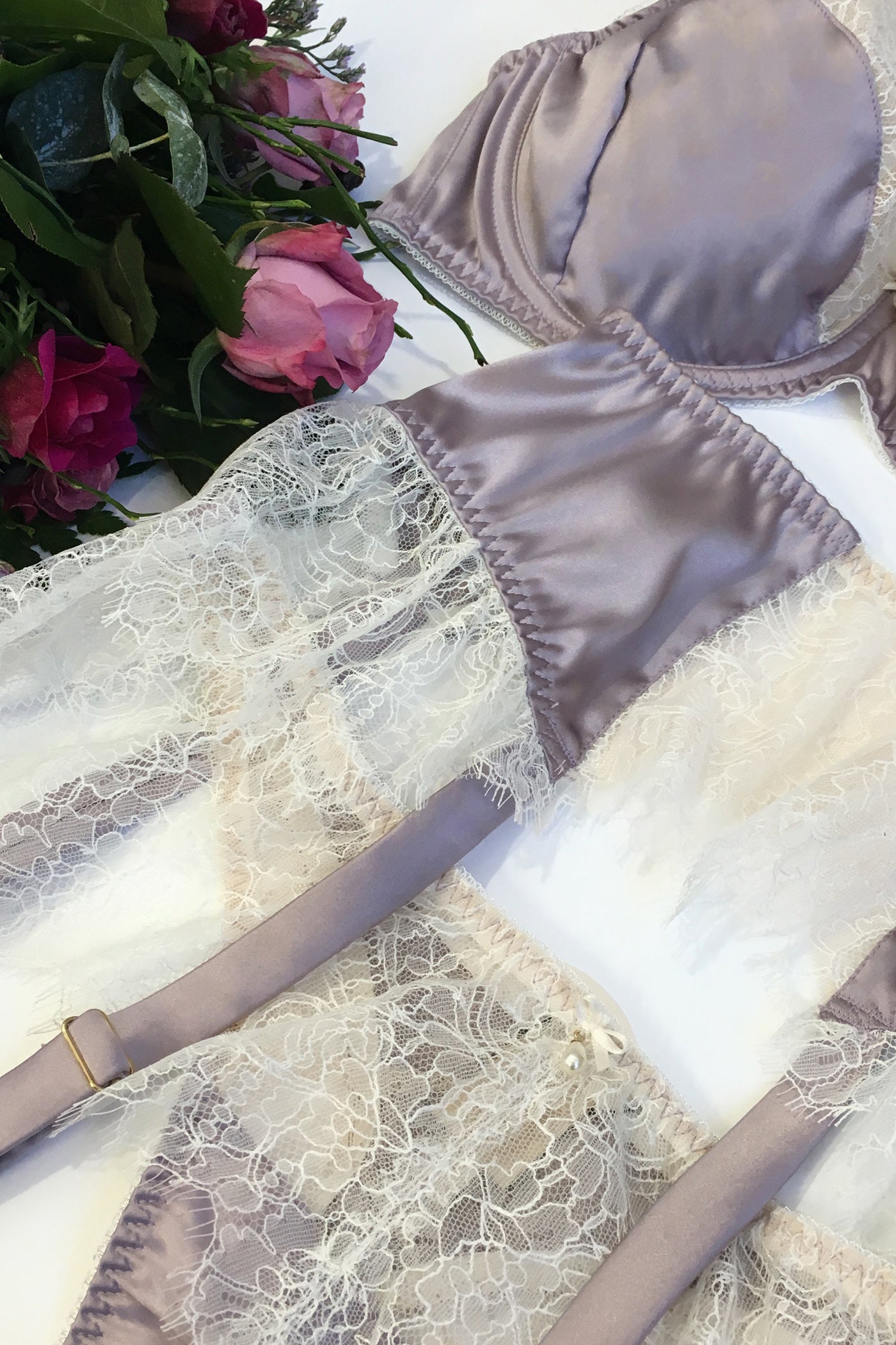 Vintage style lingerie set flatlay with garter belt, bra and thong in lilac silk and white lace