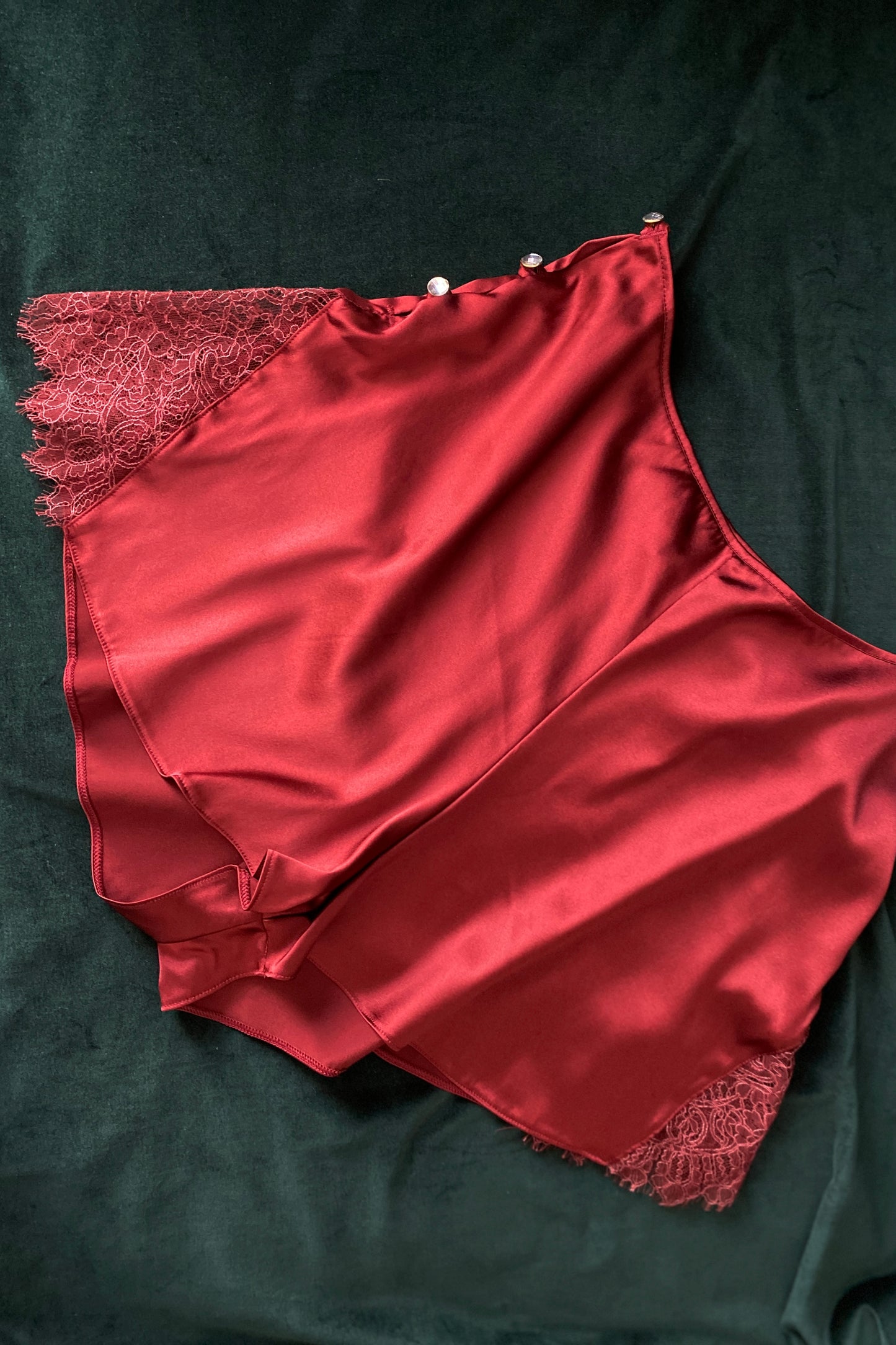 Flat lay of luxury red silk and lace French knickers with crystal buttons