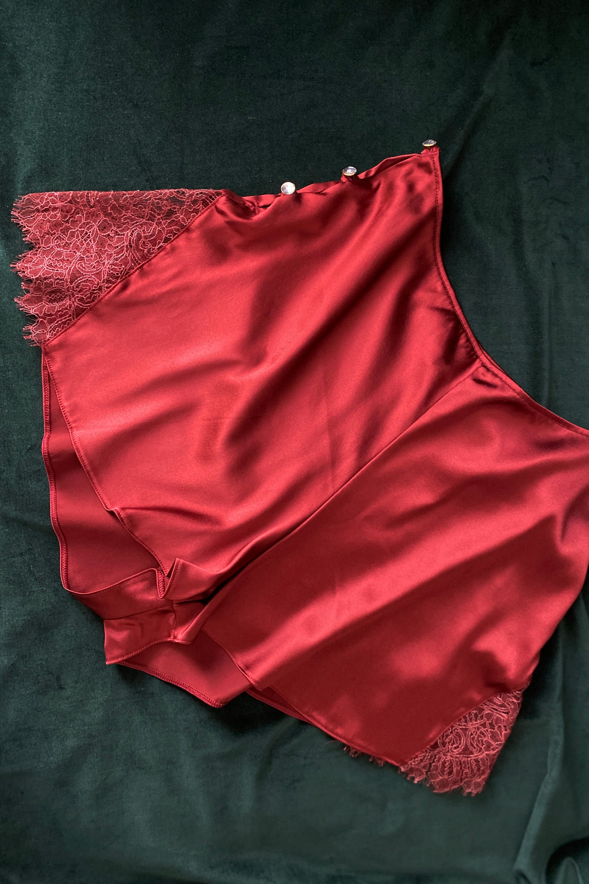 Flat lay of luxury red silk and lace French knickers with crystal buttons