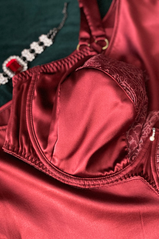 Close up of dark red silk bra cup, with matching red lace top cup and gold ring adjusters